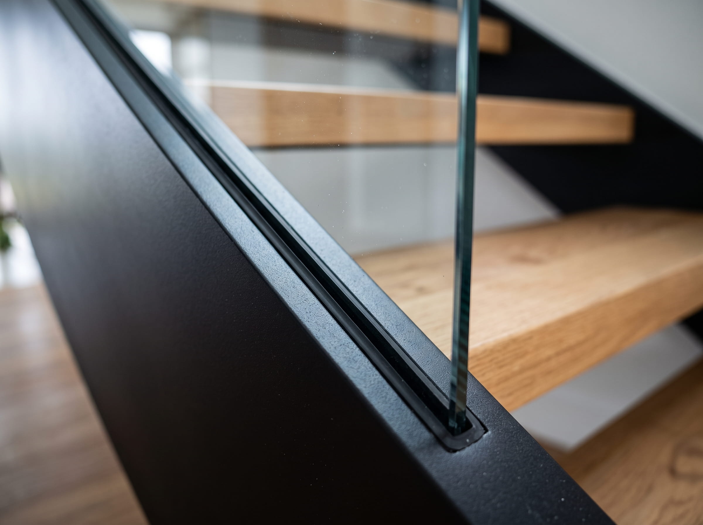 Curved structural glass panel recessed into a steel stair stringer