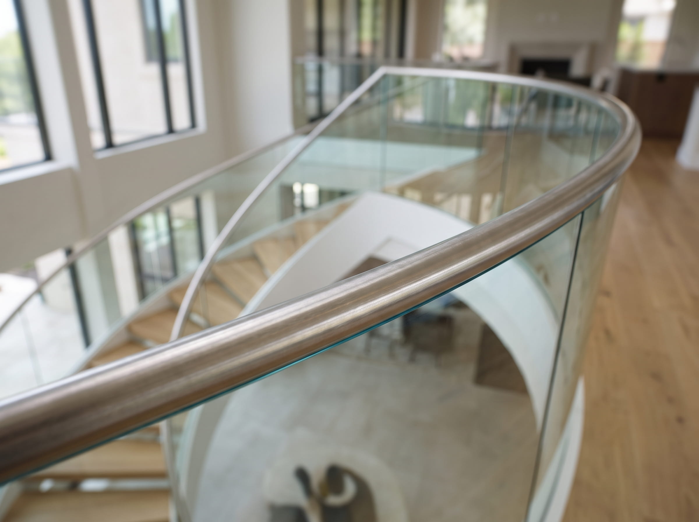 Brushed stainless steel top handrail fitted on curved staircase glass